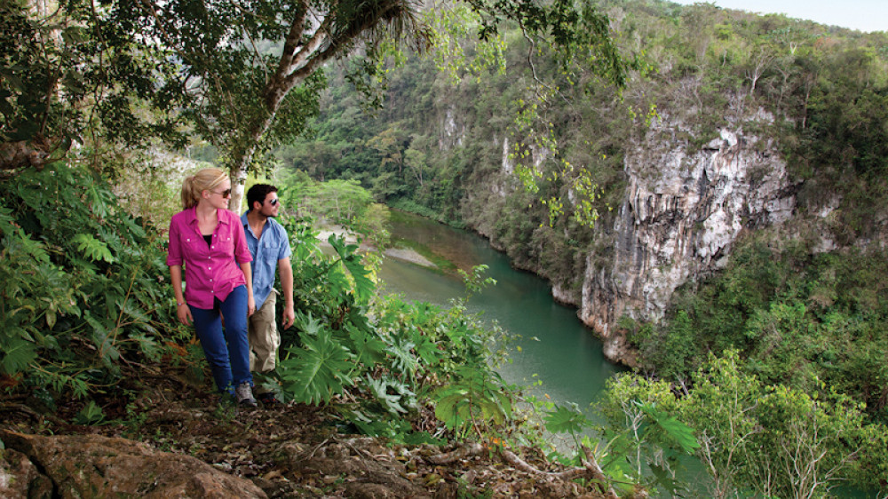 2 junge Leute wandern in der Nähe von Baracoa am Fluss entlang. grüne Vegetation und Fluss ()
