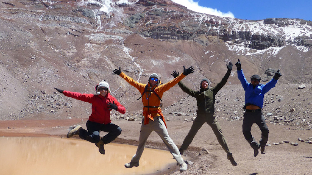 Eine Gruppe hüpft vor dem Chimborazo Vulkan. ()